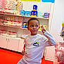 Ibrahima participe au concours pour gagner de l'argent avec cette photo : child, boy, candy_store, lollipop, peace_sign, sweets, shelf, colorful, smiling, casual_clothing, white_shirt, indoor, retail, snack, food, happy, playful, young, person, bright_colors