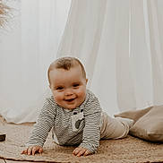 Jules a rejoint le concours — aidez-le/la à gagner de superbes lots ! baby, crawling, smile, striped_clothing, rug, pillow, candles, wooden_floor, vase, pampas_grass, curtains, indoor, child, portrait, happy, cozy, soft_light, floor, homedecor, infant