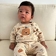 Lorenzo is registered to the contest to win money with this photo: baby, child, infant, pumpkin, sweater, pants, yellow_socks, couch, indoor, curious, sitting, face, person, clothing, cozy, soft_fabric, expression, looking_up, cute, homedecor