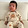 baby, child, infant, pumpkin, sweater, pants, yellow_socks, couch, indoor, curious, sitting, face, person, clothing, cozy, soft_fabric, expression, looking_up, cute, homedecor