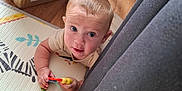 Sebastian is registered to the contest to win money with this photo: baby, blue_eyes, cardboard_box, child, couch, crawling, curious, flooring, furniture, indoor, light_skin, lion_pattern, person, play_mat, playtime, short_hair, smiling, toddler, toy, wooden_chair