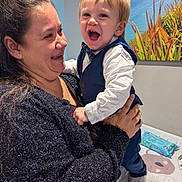 Sebastian joined the competition — help win amazing prizes! child, toddler, woman, smile, laughing, vest, bow_tie, holding, indoor, portrait, happy, clothing, baby_wipes, painting, wall, person, face, long_hair, sweater, family