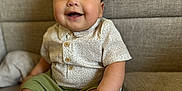 Owen joined the competition — help win amazing prizes! baby, child, smile, happy, sitting, indoor, couch, clothing, shirt, shorts, shoes, socks, face, person, infant, cute, joyful, home, portrait, young