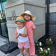 Ayla joined the competition — help win amazing prizes! child, children, smiling, hat, balloons, outdoor, sidewalk, flowers, plants, building, concrete, window, footwear, shorts, tank_top, dress, happy, person, portrait, sunhat