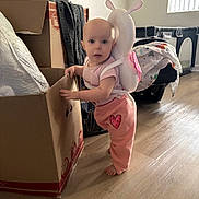 Cozette joined the competition — help win amazing prizes! baby, child, pink_clothing, snail_backpack, cardboard_box, wooden_floor, indoor, window_light, playpen, blanket, toy, barefoot, curious, standing, home, infant, cute, decor, person, young_child