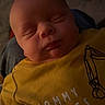Jayce is registered to the contest to win money with this photo: baby, sleeping, yellow_shirt, text_on_clothing, infant, child, face, head, closed_eyes, cute, cozy, warm_lighting, person, clothing, resting, portrait, indoor, soft_light, newborn, expressionless