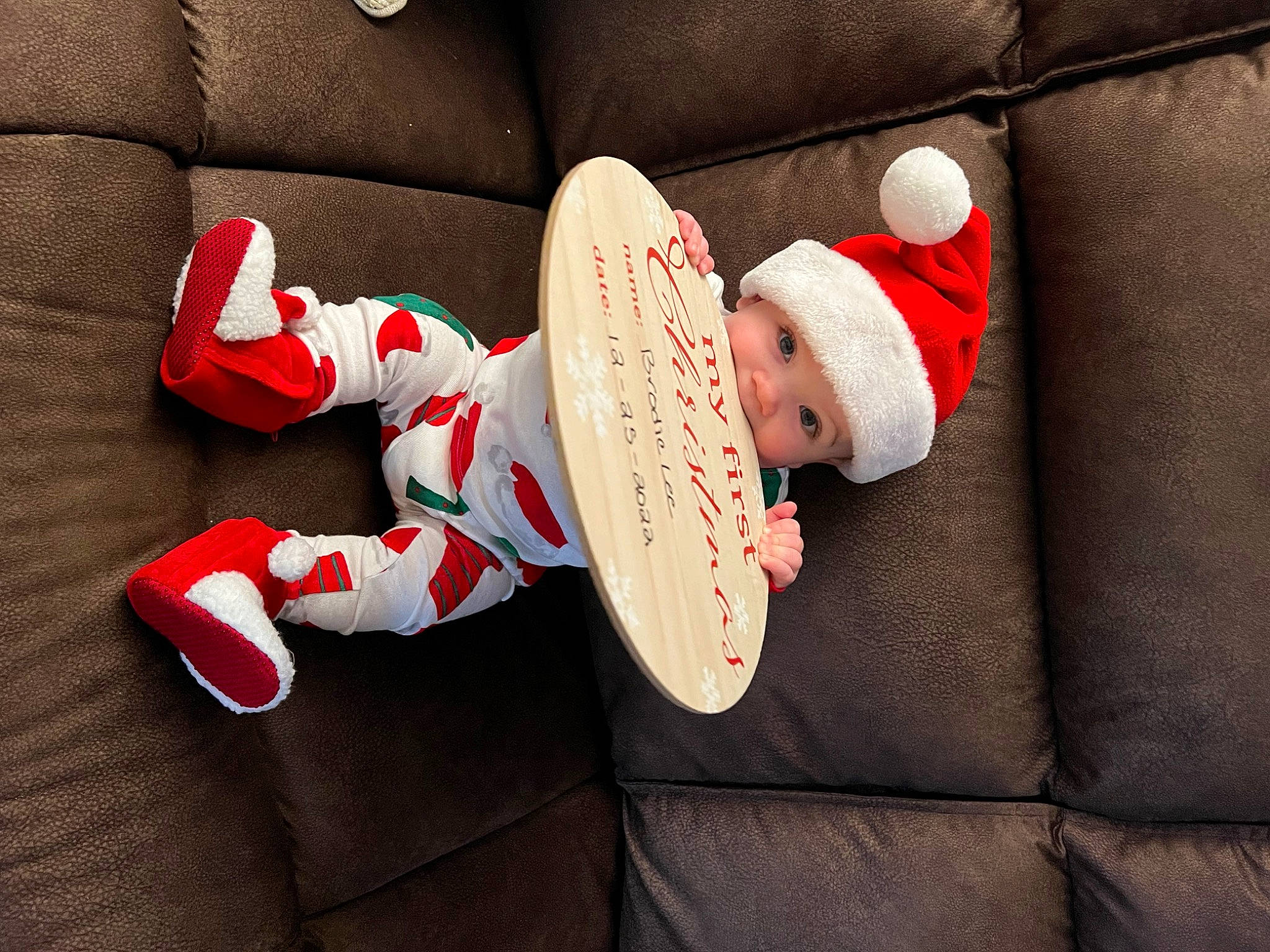 Brodie is registered to the contest to win money with this photo: baby, baby_sleeping, baby_toddler_clothing, comfort, costume_hat, couch, event, fictional_character, finger, foot, hat, headwear, holiday, human_body, lap, person, santa_claus, sleeve, sock, toddler
