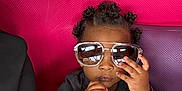 Pharell a rejoint le concours — aidez-le/la à gagner de superbes lots ! toddler, child, sunglasses, hand, adult_hand, curly_hair, black_clothing, pink_background, purple_background, textured_wall, portrait, indoor, cute, fashion, accessory, person, skin, face, nail, holding_hand