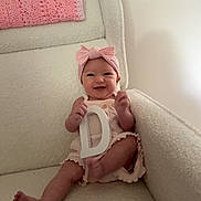Vaeda joined the competition — help win amazing prizes! baby, child, smile, pink_headband, letter_d, armchair, knitted_blanket, soft_texture, indoor, happy, infant, cute, light_clothing, cozy, seated, furniture, portrait, person, home, relaxed