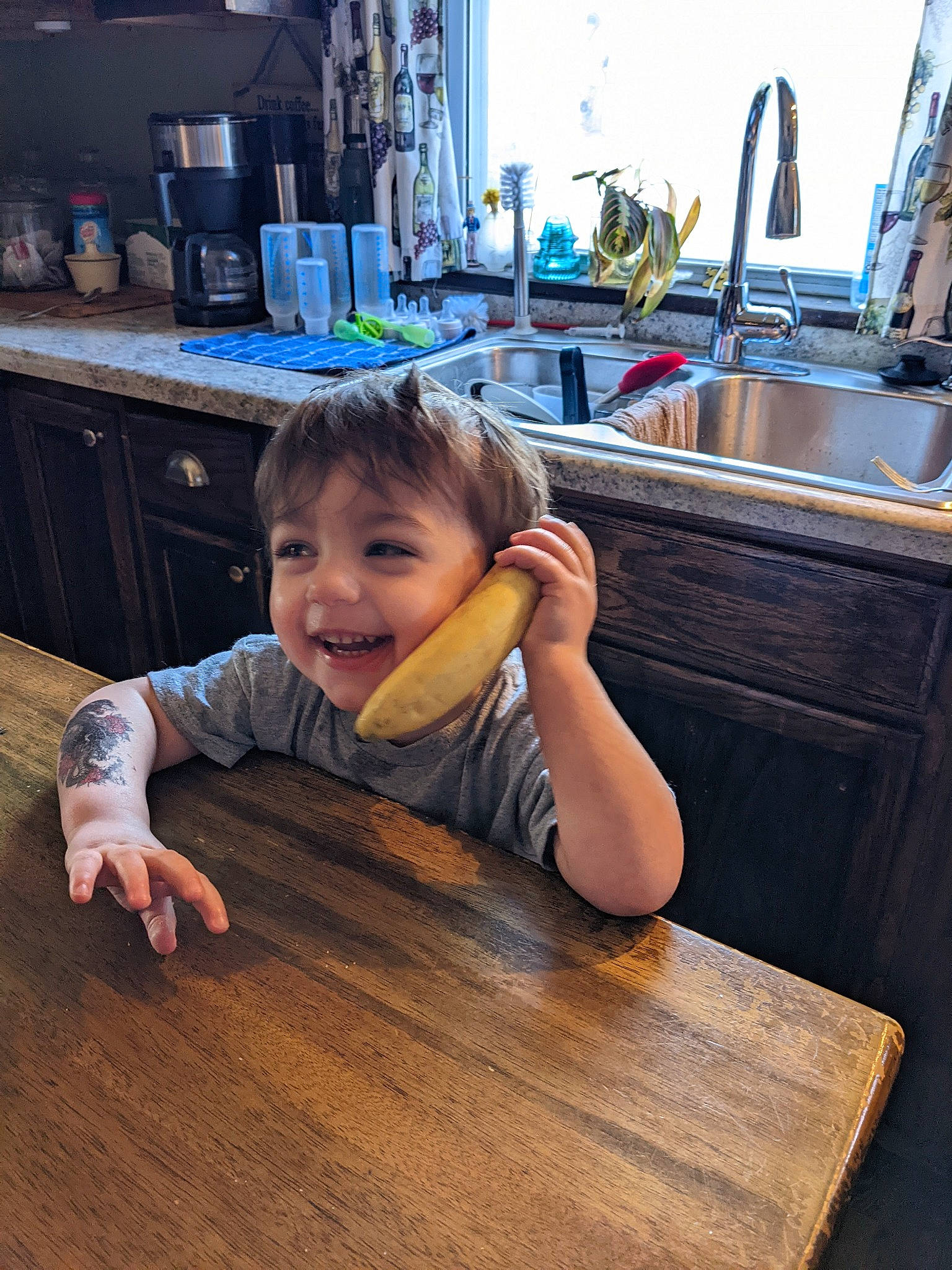 Weylin is registered to the contest to win money with this photo: baby_toddler_clothing, cabinetry, child, countertop, desk, floor, flooring, fun, happy, hardwood, joy, kitchen, person, plumbing_fixture, sink, table, tableware, tap, toddler, varnish