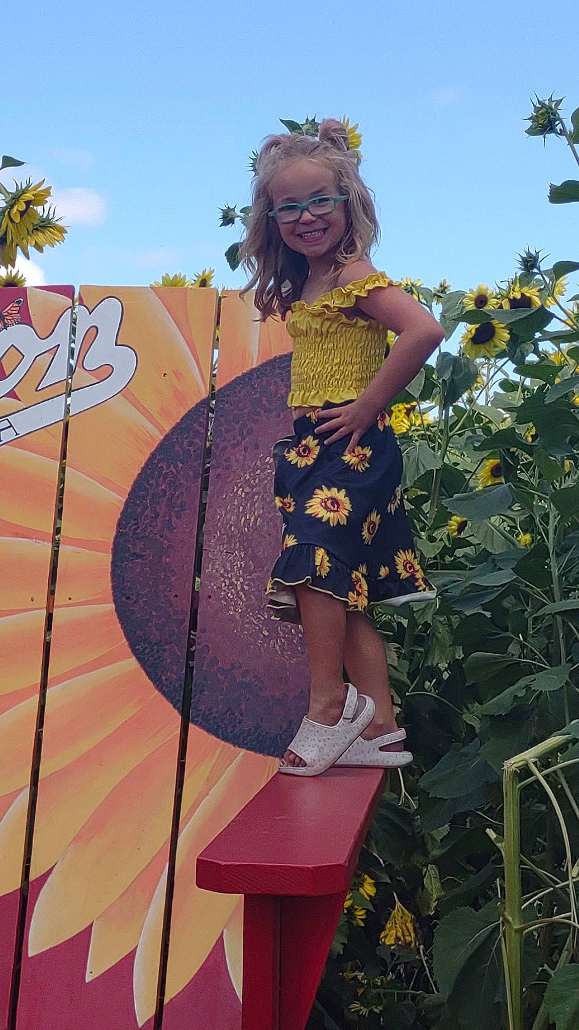 Paislee is registered to the contest to win money with this photo: costume, dress, eyewear, fashion_design, flower, fun, happy, joy, leisure, magenta, pattern, people_in_nature, person, pink, plant, sandal, sky, smile, sunflower, tree