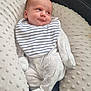 baby, infant, onesie, bib, pillow, couch, leather, face, expression, soft_texture, patterned_clothing, striped, lying_down, indoors, cute, comfortable, child, newborn, resting, cozy