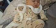 William is registered to the contest to win money with this photo: baby, sleeping, plush_toy, lamb, onesie, bed, pillow, blanket, infant, child, soft_toy, cozy, cute, peaceful, indoors, fabric, comfort, nap, person, sleep