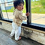 Niko joined the competition — help win amazing prizes! toddler, child, curly_hair, barefoot, window, wooden_bench, indoor, shirt, pants, standing, looking_outside, daylight, expression, curious, young_child, casual_clothing, natural_light, brick_wall, home_interior, portrait