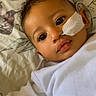 Naavya joined the competition — help win amazing prizes! baby, infant, face, medical_tube, white_clothing, lying_down, bedspread, floral_pattern, closeup, skin, eyes, mouth, cheek, curly_hair, indoors, person, cute, healthcare, resting, young_child