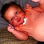 Aaliyah joined the competition — help win amazing prizes! baby, infant, child, face, fist, clothing, peach_outfit, pillow, pattern, blanket, skin, head, arm, person, indoor, cute, smile, lying_down, newborn, raised_fists