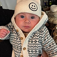 Louis participe au concours pour gagner de l'argent avec cette photo : baby, child, face, hat, beanie, smile, sweater, knitwear, pattern, hand, fingers, person, portrait, indoors, warm_clothing, cute, blue_eyes, holding, cozy, expression