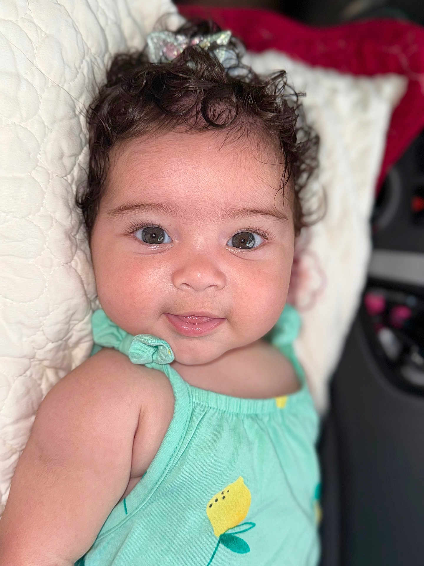 Emilly joined the competition — help win amazing prizes! baby, child, curly_hair, smile, mint_green, lemon_print, pillow, quilted, face, eyes, infant, cute, skin, clothing, portrait, lying_down, indoors, head, person, happy