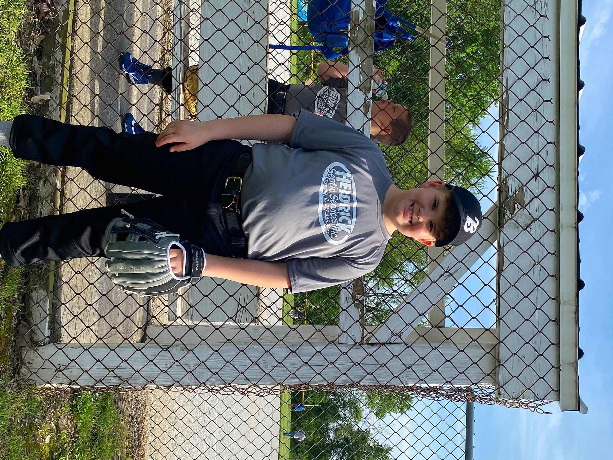 Erik is registered to the contest to win money with this photo: chain_link_fencing, fence, fun, grass, headwear, human_leg, joy, leisure, mesh, net, people_in_nature, person, recreation, sky, smile, thigh, tree, walking_shoe, white, wire_fencing
