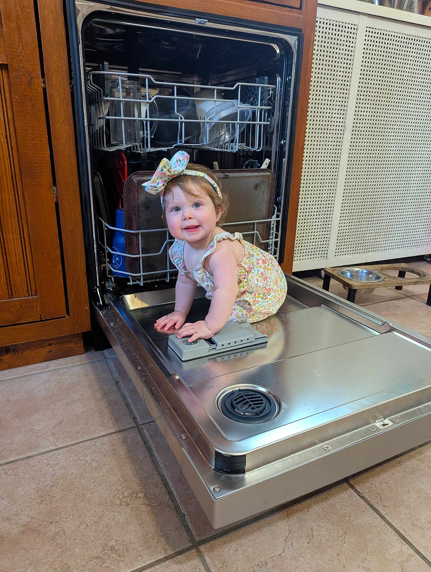 Remington joined the competition — help win amazing prizes! baby, child, dishwasher, kitchen, floor, tile, metal, cabinet, appliance, smiling, headband, clothing, curly_hair, cute, sitting, indoors, face, person, young_child, playful