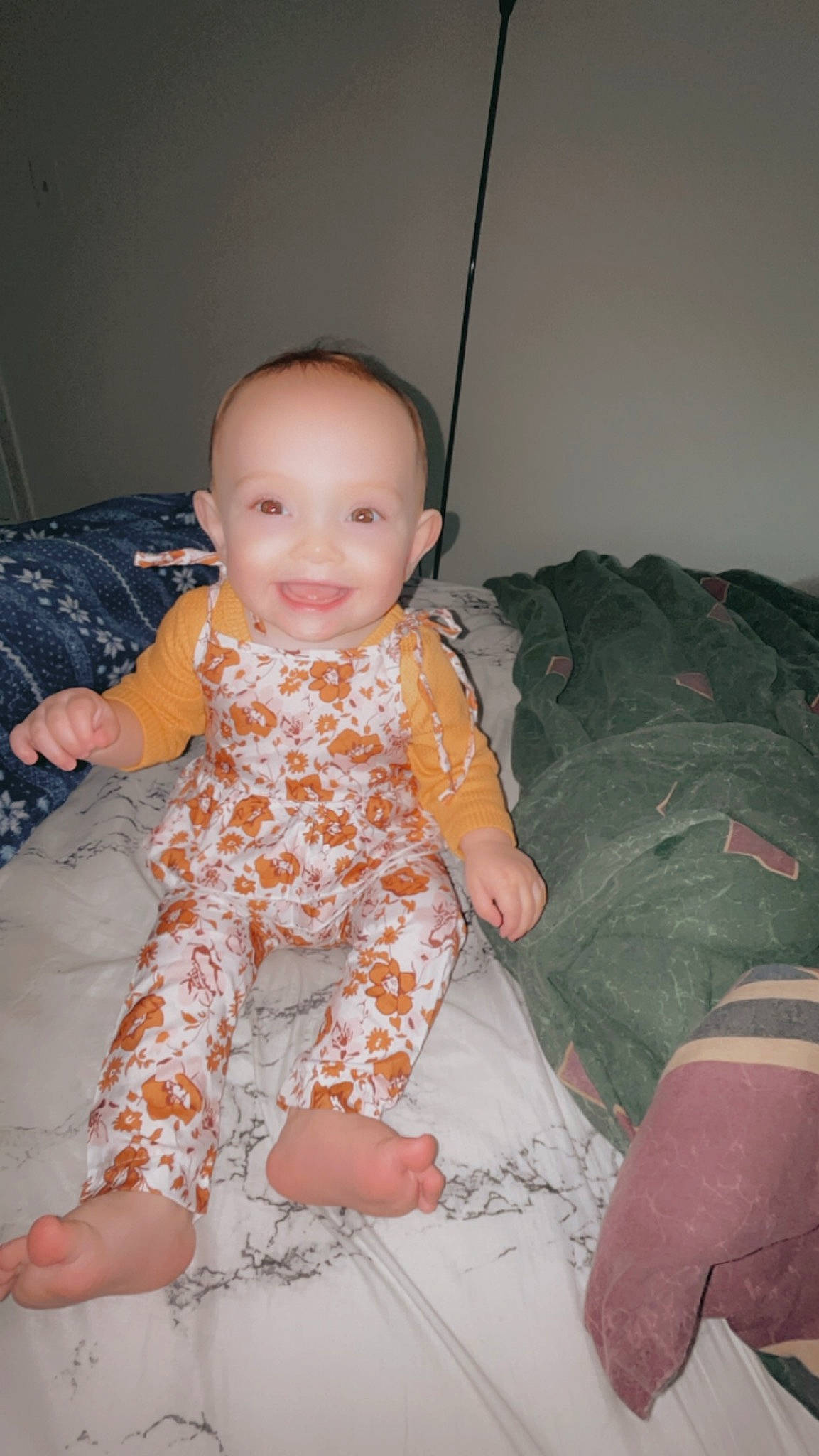 Nova is registered to the contest to win money with this photo: baby, baby_toddler_clothing, comfort, eye, finger, flooring, foot, fun, happy, human_body, human_leg, joy, linens, pattern, person, room, sitting, skin, sleeve, smile