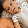 toddler, child, baby, white_onesie, bed, skin, arm, face, eyes, mouth, lying_down, indoor, closeup, person, curious, infant, candid, soft_light, human, portrait