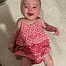 baby, child, smile, happy, dress, red, white, floral_pattern, infant, cute, lying_down, fabric, footwear, person, skin, indoors, texture, closeup, young, joy