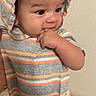 River joined the competition — help win amazing prizes! baby, bed, candid, chewing, child, colorful_blanket, curious, eyes, face, finger, gray_clothing, hand, hood, indoors, infant, orange_stripes, portrait, sitting, striped_clothing, wall