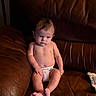River is registered to the contest to win money with this photo: baby, bare_feet, brown, centered_subject, child, couch, diaper, eyes, face, furniture, hair, home, indoor, infant, leather_sofa, legs, photography, portrait, serious_expression, sitting