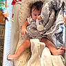 baby, baby_clothing, bassinet, blanket, bottle, child, colorful, cozy, cushion, drinking, family_photo, indoors, infant, lying_down, nursery, play_gym, portrait, sleeping_area, star_pattern, toy