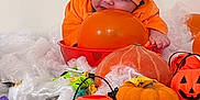 Nyna a rejoint le concours — aidez-le/la à gagner de superbes lots ! baby, pumpkin_costume, orange_balloon, halloween, candy, pumpkin, decorations, fake_spider_web, table, orange, green_wrappers, purple_wrappers, plastic_jack_o_lantern, cute, infant, holiday, celebration, festive, costume, smiling