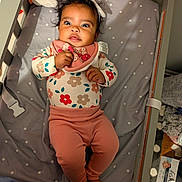 Kataleya is registered to the contest to win money with this photo: baby, bib, blanket, child, crib, cute, expression, feet, floral_outfit, hand, headband, indoor, infant, lying_down, person, pink_pants, polka_dot, sleeping_area, soft_toy, wide_eyes