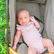 Gracelynn Leigh is registered to the contest to win money with this photo: baby, infant, stroller, pink_clothing, blue_eyes, tongue_out, outdoor, grass, sunlight, cute, child, person, seat, fabric, baby_toy, playful, summer, portrait, relaxing, young