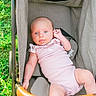 baby, infant, stroller, pink_clothing, blue_eyes, tongue_out, outdoor, grass, sunlight, cute, child, person, seat, fabric, baby_toy, playful, summer, portrait, relaxing, young