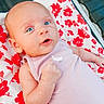 baby, infant, blue_eyes, onesie, pink_clothing, blanket, red_flowers, floral_pattern, cute, portrait, young_child, skin, hand, lying_down, indoors, soft_light, expression, person, newborn, resting