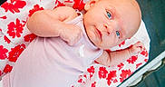 Gracelynn Leigh is registered to the contest to win money with this photo: baby, infant, blue_eyes, onesie, blanket, floral_pattern, red_flowers, white_background, cute, lying_down, child, person, skin, soft_fabric, newborn, portrait, small_hand, face, awake, indoors