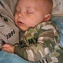 baby, sleeping, blanket, pajamas, camo, child, cozy, infant, face, closed_eyes, soft, cute, rest, comfort, peaceful, warm, person, toddler, indoors, nap