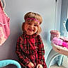 child, girl, smile, plaid_dress, headband, indoor, toy, chair, vanity_table, pink, blue, happy, young, person, furniture, cute, playroom, hair, face, sitting