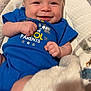 baby, infant, smiling, blue_onesie, blanket, baby_seat, cushion, cute, happy, child, young, portrait, indoor, soft_toy, cozy, skin, head, hands, small, comfort