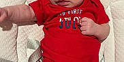 Eastyn joined the competition — help win amazing prizes! baby, infant, red_onesie, baby_seat, cushion, face, legs, feet, arms, skin, person, newborn, clothing, cute, indoors, expression, small, child, comfort, sitting