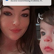 Emery is registered to the contest to win money with this photo: baby, infant, mother, woman, child, portrait, selfie, face, eyes, smiling, family, indoor, bookshelf, books, smartphone, lock_screen, notification, polka_dot_clothing, close_up, home