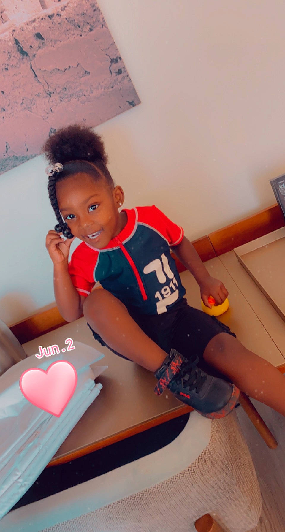 A'Mari is registered to the contest to win money with this photo: arm, carmine, chair, child, elbow, eyewear, flooring, fun, happy, human_leg, joy, knee, leisure, person, room, shorts, sleeve, sportswear, t_shirt, table