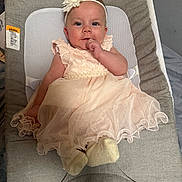 Mila is registered to the contest to win money with this photo: baby, infant, child, dress, headband, flower, seated, baby_seat, cushion, indoor, cute, portrait, soft_lighting, clothing, footwear, hand, face, smile, blue_eyes, curious