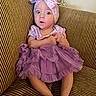Jayla is registered to the contest to win money with this photo: baby, barefoot, bow, child, clothing, couch, cute, dress, expression, furniture, headband, indoors, legs, person, purple, seated, striped, surprised, toddler, wide_eyes