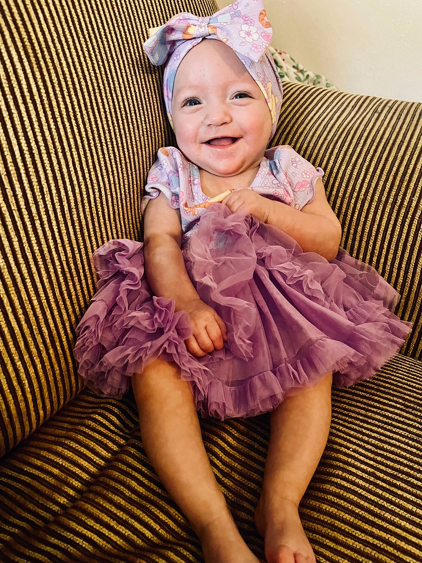 Jayla joined the competition — help win amazing prizes! baby, child, clothing, couch, cute, dress, fabric, furniture, happy, headband, indoors, infant, person, portrait, purple, sitting, smiling, striped, toddler, young