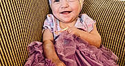 Jayla joined the competition — help win amazing prizes! baby, bow, child, clothing, couch, cute, dress, face, hand, happy, headband, indoors, infant, person, portrait, purple, sitting, smile, striped, toddler