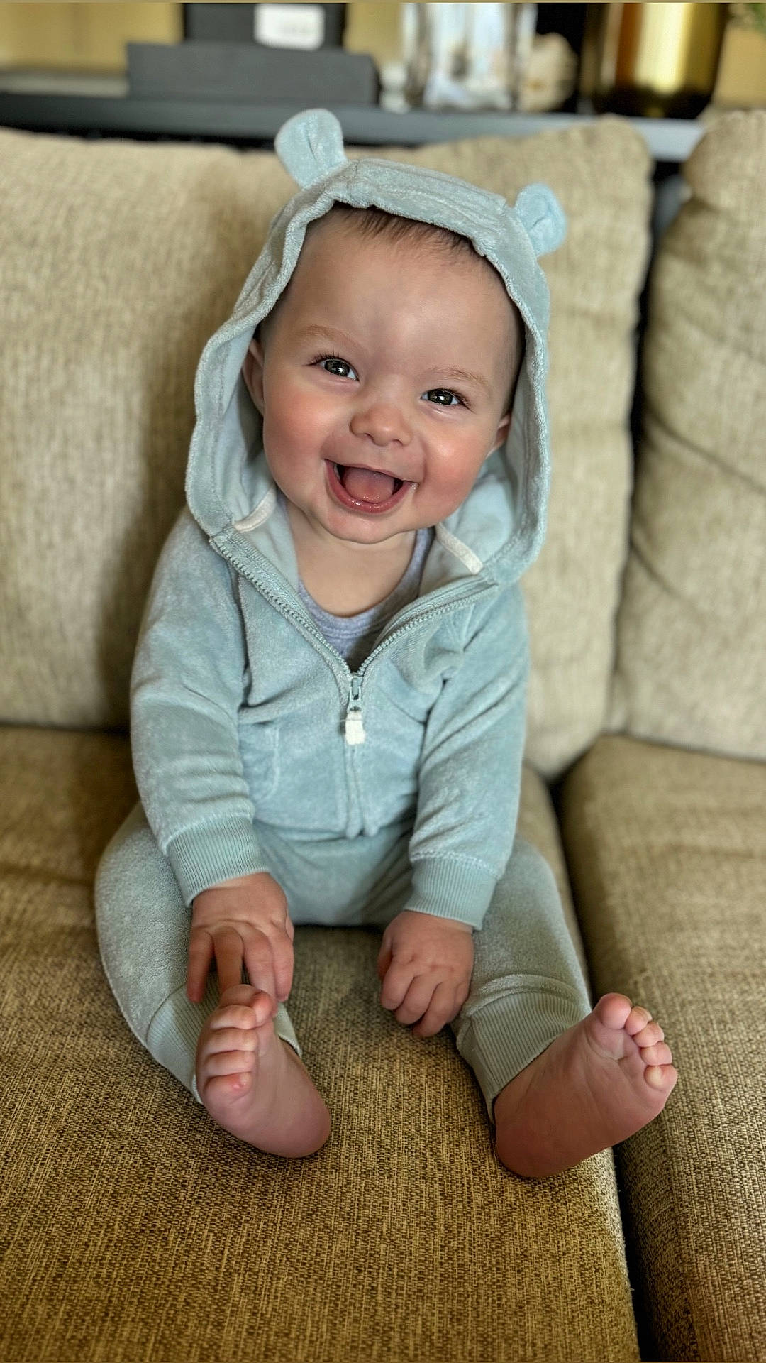 Owen joined the competition — help win amazing prizes! baby, babylaughing, clothing, coat, couch, cushion, face, furniture, happy, hat, head, homedecor, hood, jacket, pants, person, photography, portrait, sitting, smile
