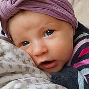 Romane participe au concours pour gagner de l'argent avec cette photo : baby, close_up, headband, purple, blanket, stars, face, expression, eyes, mouth, sweater, stripes, cute, infant, sleepy, soft, texture, cozy, indoors, portrait