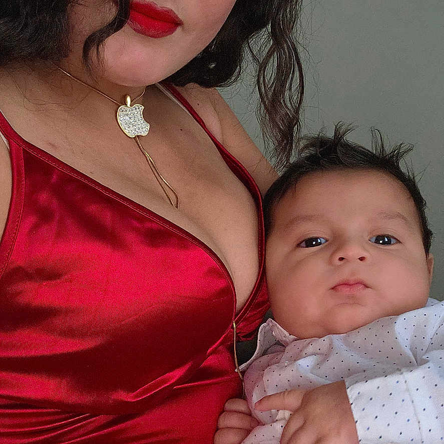 Karla Bermúdez is registered to the contest to win money with this photo: woman, baby, red_dress, portrait, indoor, face, person, clothing, child, holding, casual, fashion, hair, necklace, cute, baby_clothes, expression, skin, photo, background