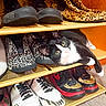 animal, black_and_white, cat, close_up, cozy, curious, feline, footwear, home, indoor, leopard_print, paws, pet, relaxing, resting, shelf, shoe_rack, shoes, sneakers, yellow_eyes